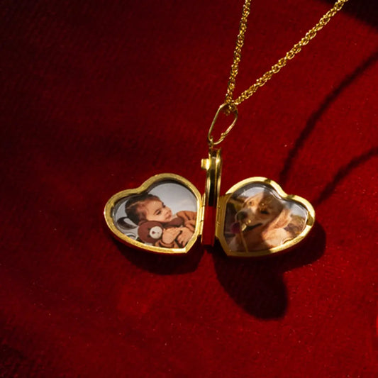 Open gold heart locket necklace on a delicate chain, showing two personalised photos inside, styled on rich red fabric.