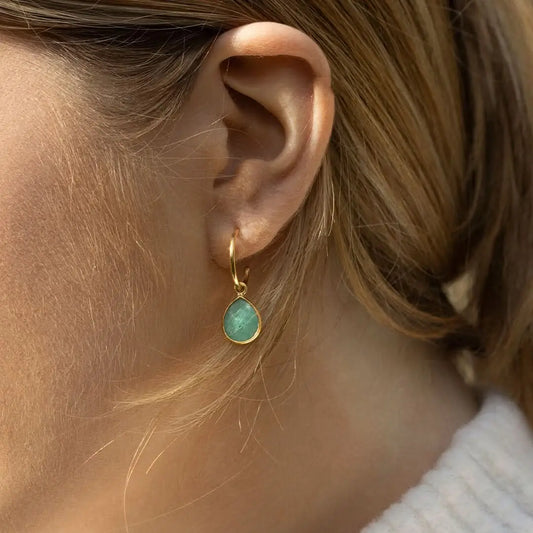 Gold hoop earrings with faceted chrysoprase teardrop gemstone worn on ear, soft natural light styling