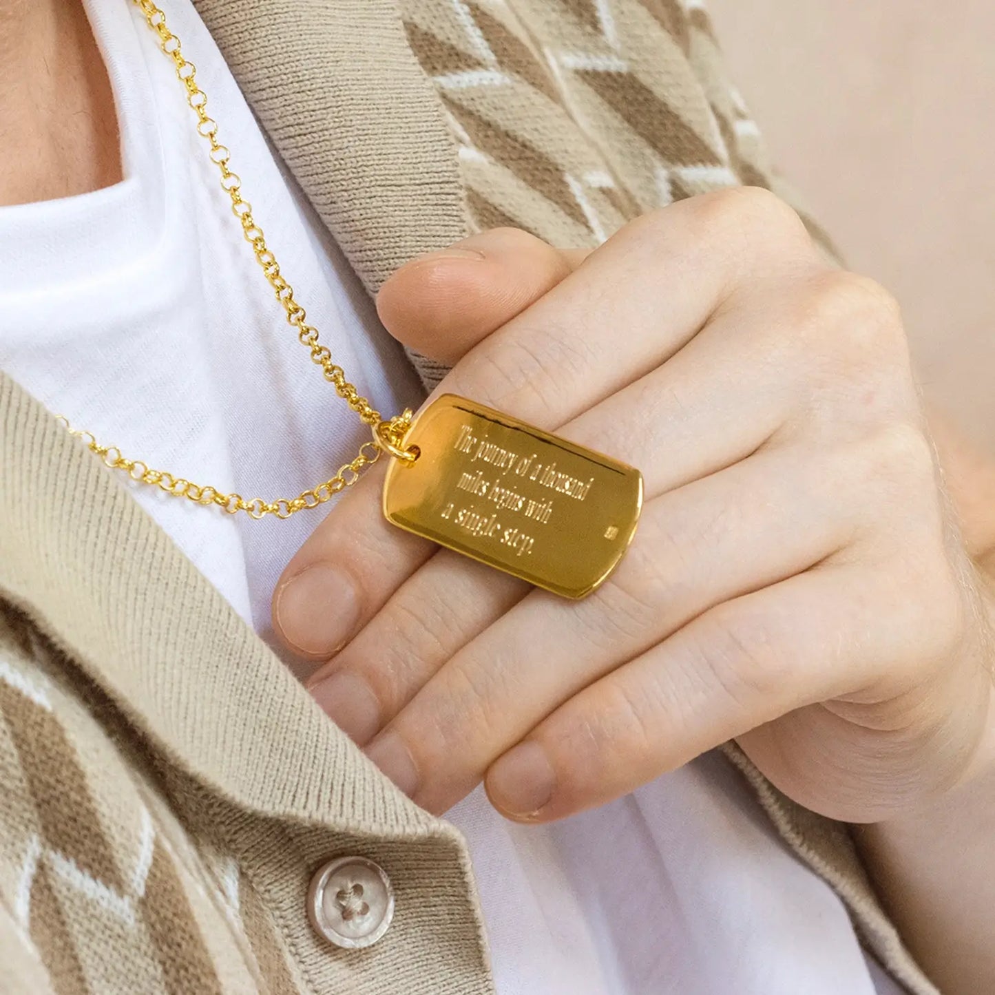 Engraved large Gold dog tag necklace held by a man