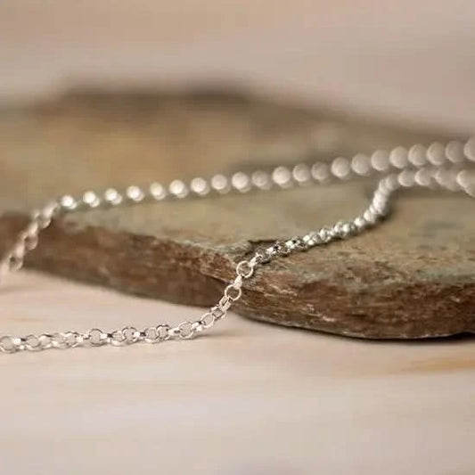white gold belcher chain necklace resting on natural stone surface, close-up detail of round links