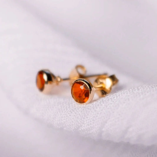 Carnelian mini stud earrings in rose gold on white fabric