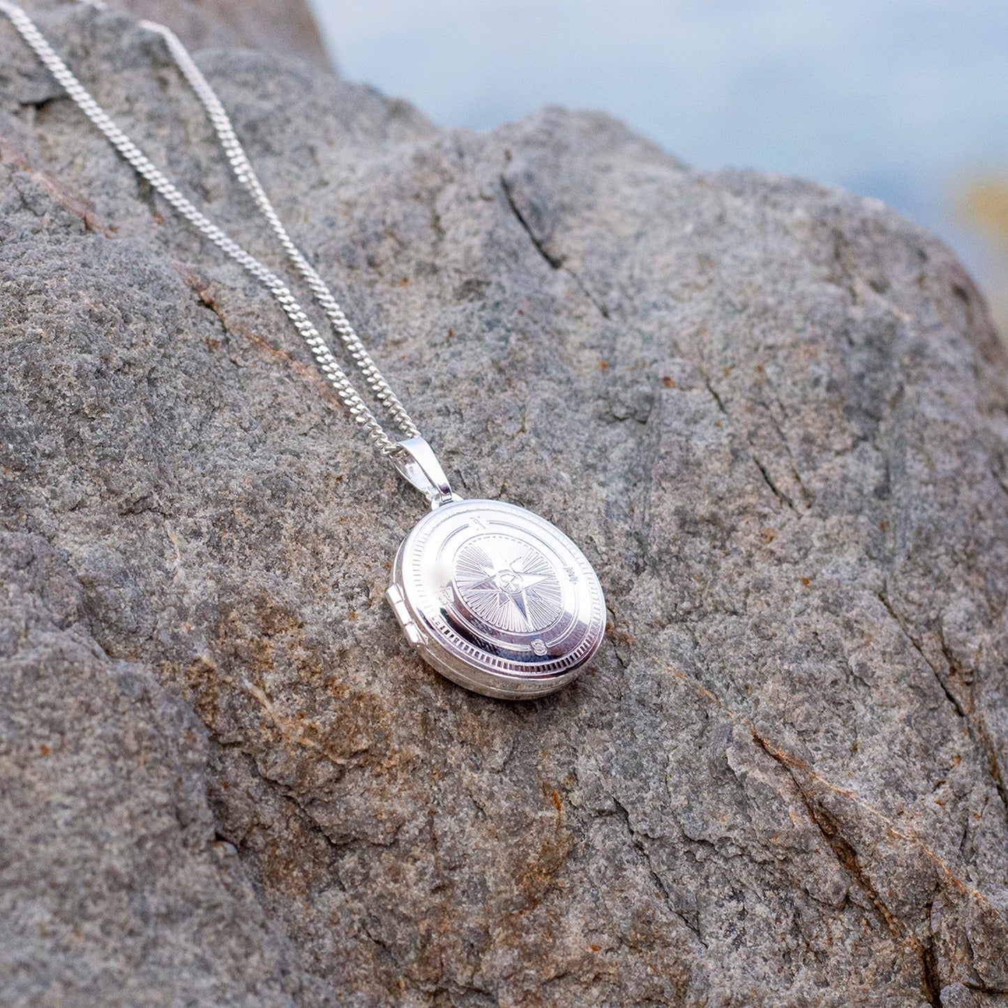 Silver locket necklace on a textured stone surface