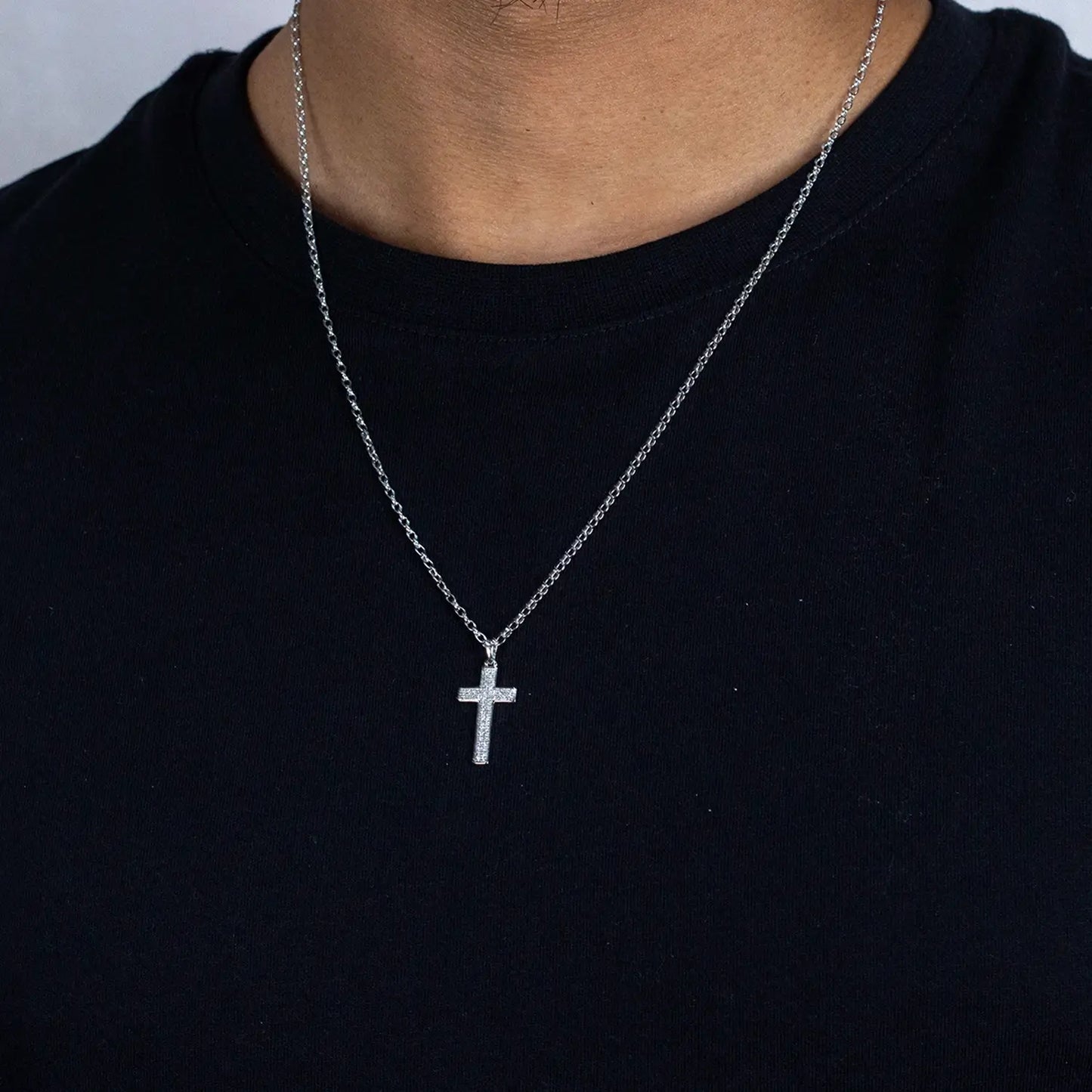 white gold cross and diamond necklace on a person wearing a black shirt