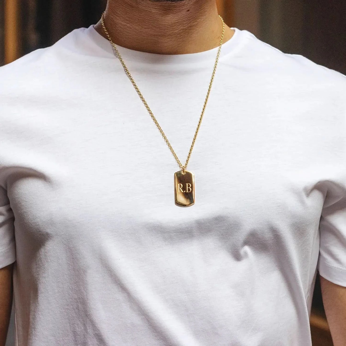 model wearing gold dogtag with front engraving