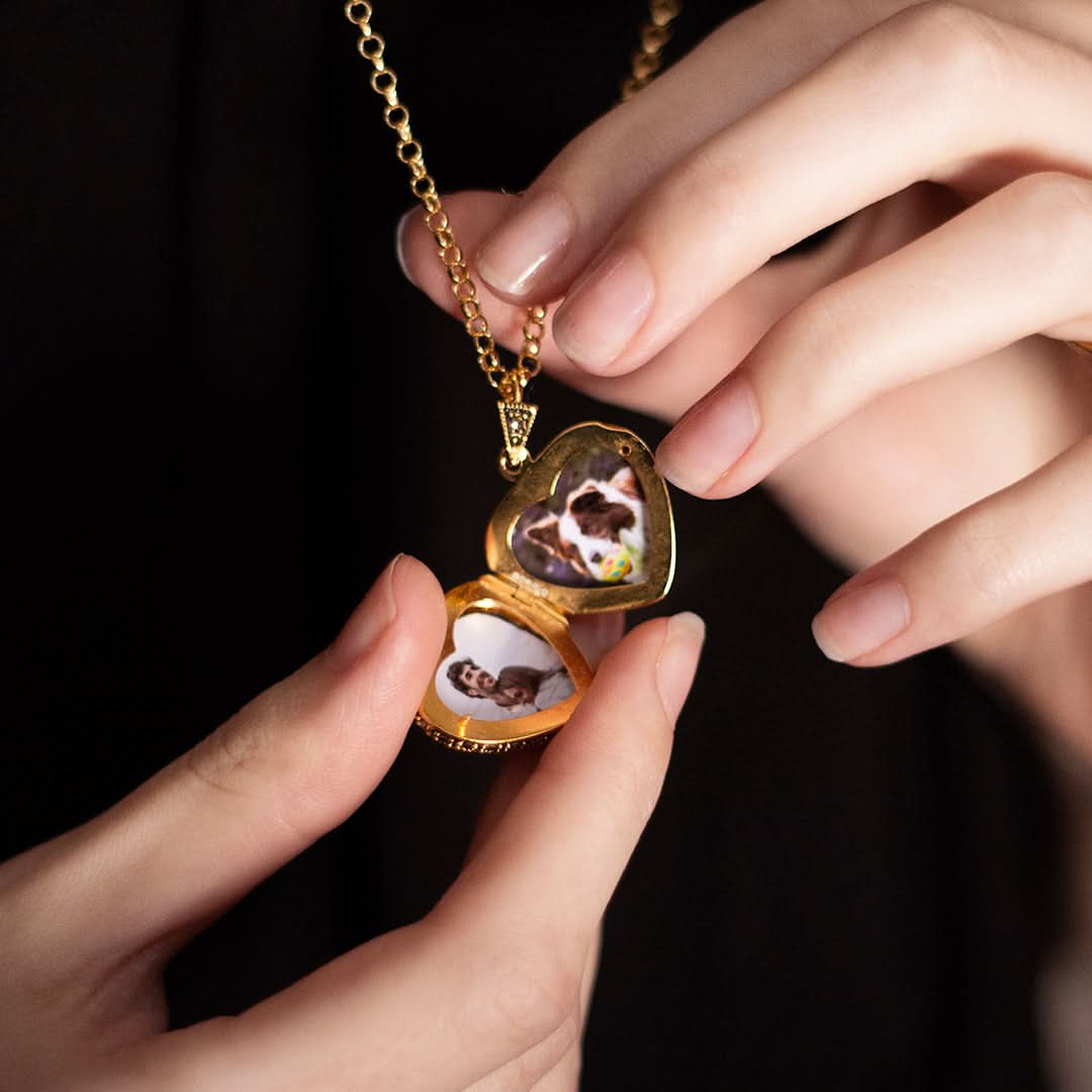 Open vintage gold heart locket necklace with pet photos inside, held in hands
