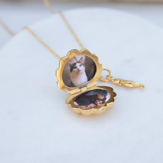 Open gold scallop shell locket necklace displaying personalised photo inserts inside, photographed on a soft white background.