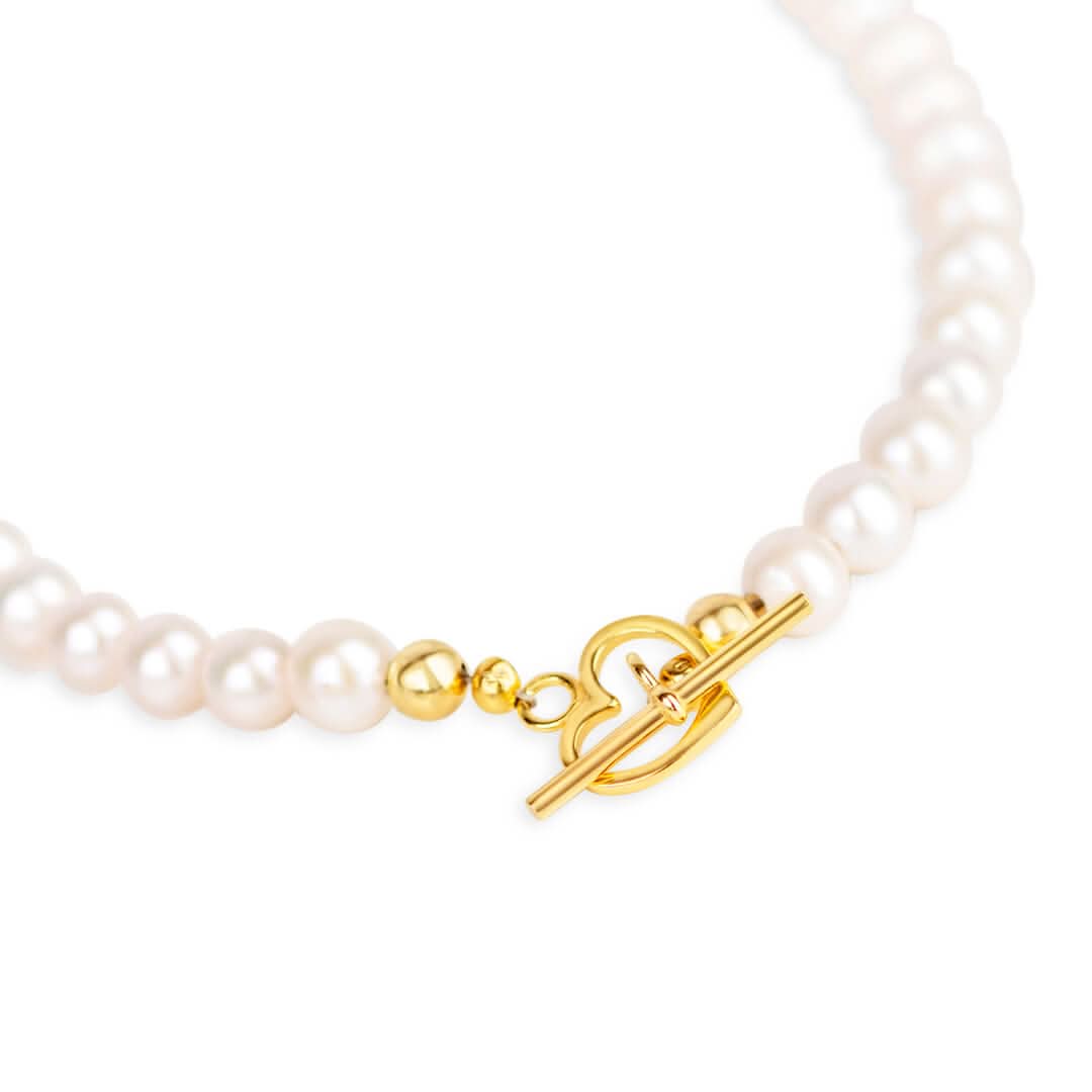 heart shaped gold catch on white pearl necklace with gold filigree heart locket