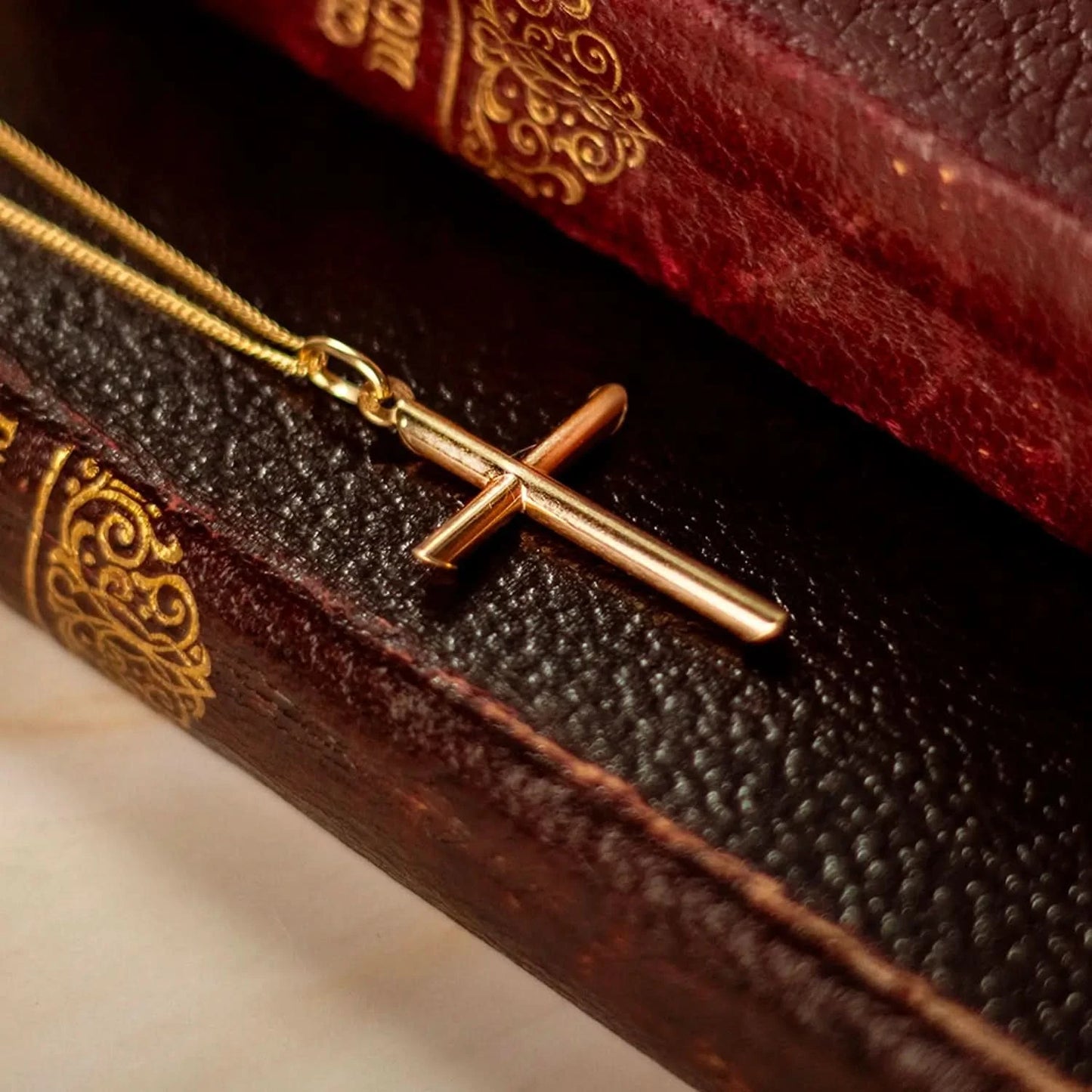 gold cross necklace, sturdy gold curb chain, high polish finish, rounded edges, solid gold men's cross pendant for men and women, sitting on leather books, bible