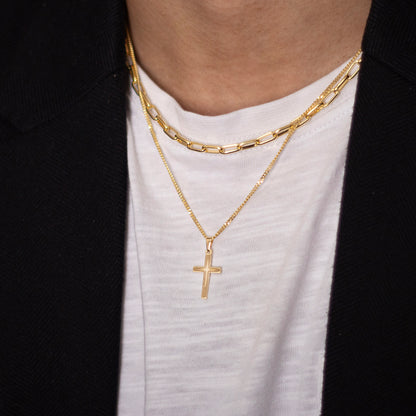 male model wearing a gold cross style necklace with a white shirt