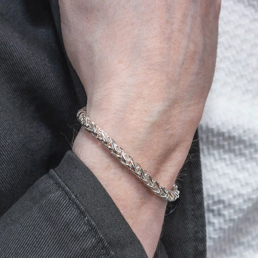 Men's sterling silver Spiga chain bracelet on a wrist with a neutral background