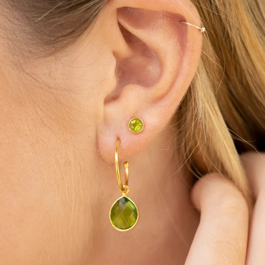 18ct gold vermeil peridot hoop earring and matching peridot stud worn on the ear, featuring faceted green peridot gemstones.