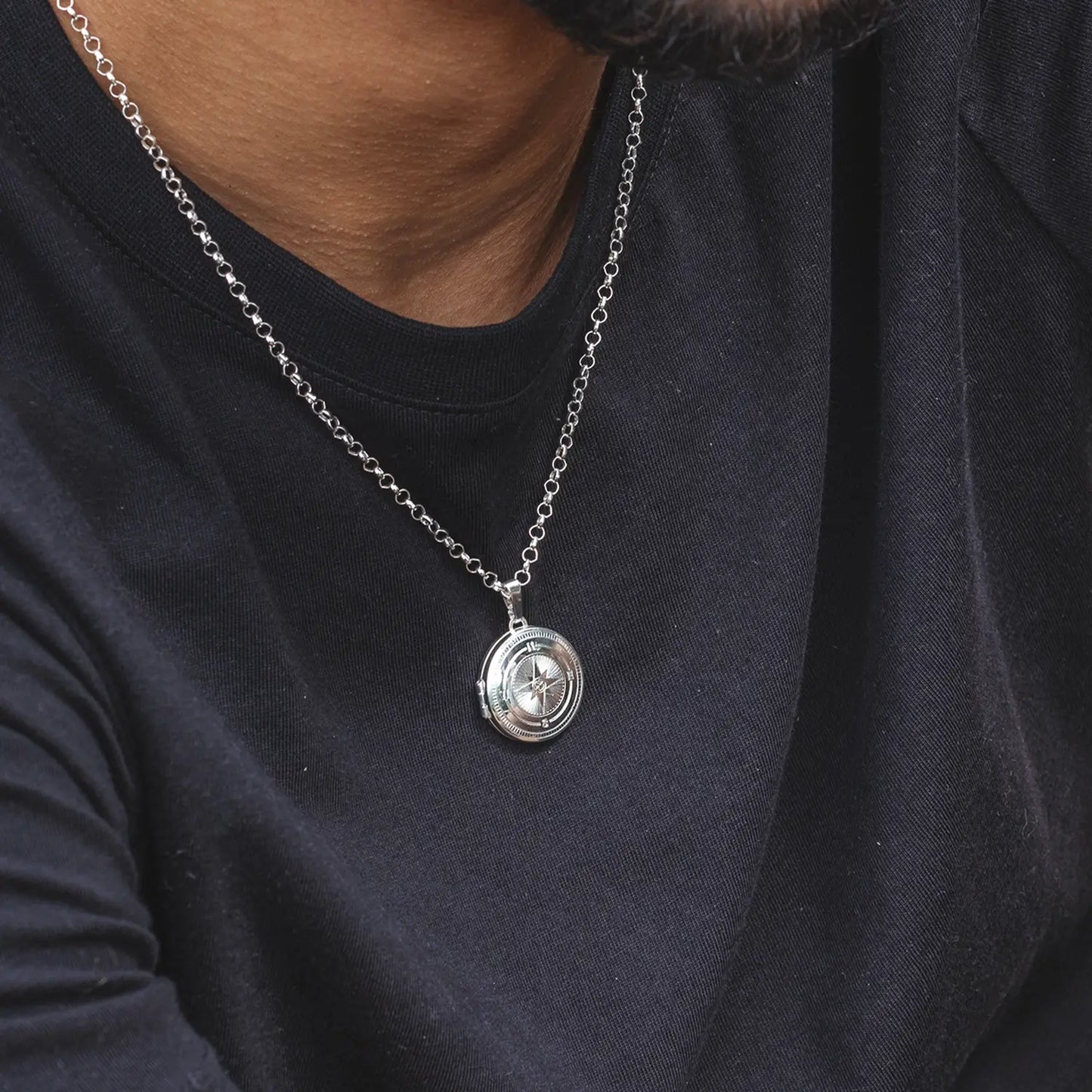 Silver compass necklace with a pendant on a person wearing a black shirt