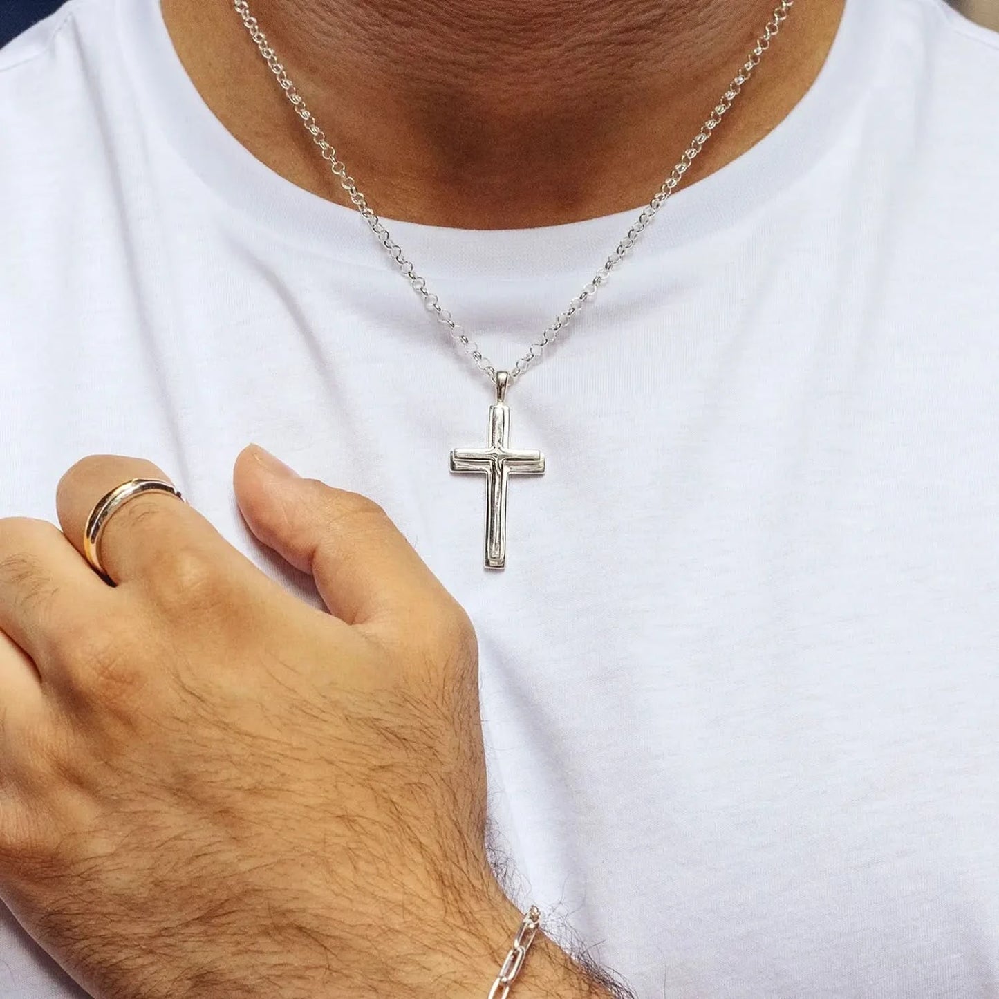 close up photograph of a silver heavy cross necklace on a belcher chain worn by a man