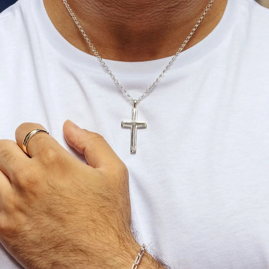 close up photograph of a silver heavy cross necklace on a belcher chain worn by a man