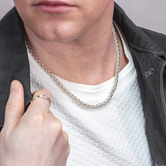 Man wearing a sterling silver spiga chain necklace with a white textured shirt and dark jacket.