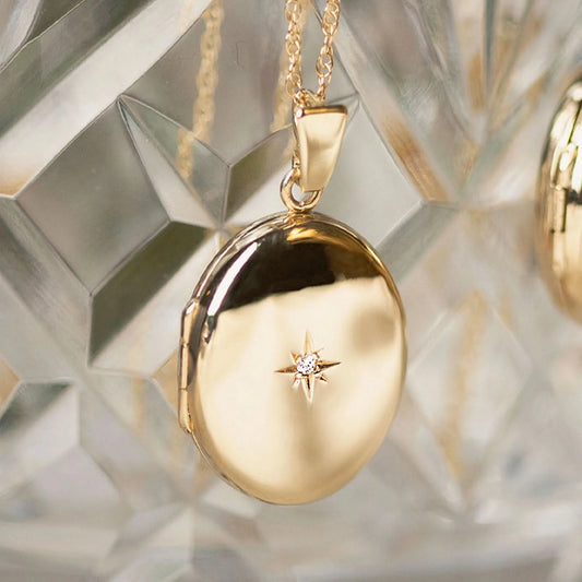 two oval diamond lockets in gold hanging out of glass