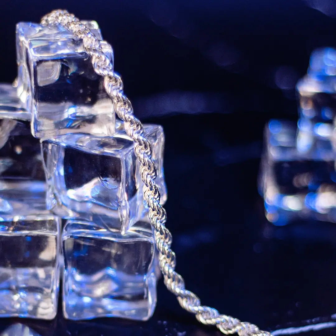 Sterling silver rope chain draped over stacked clear ice cubes with blue lighting