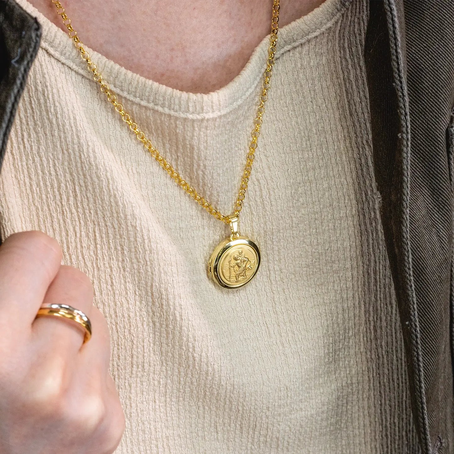 close up photograph of st christopher locket in gold showing the front of the locket on a male model