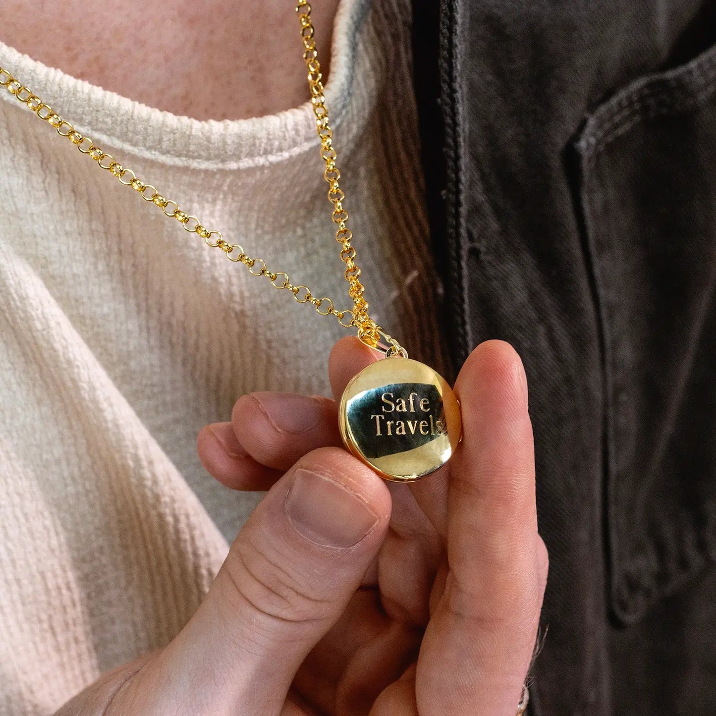 photograph of st christopher locket in gold showing the back of the locket with an engraved message worn on a male model