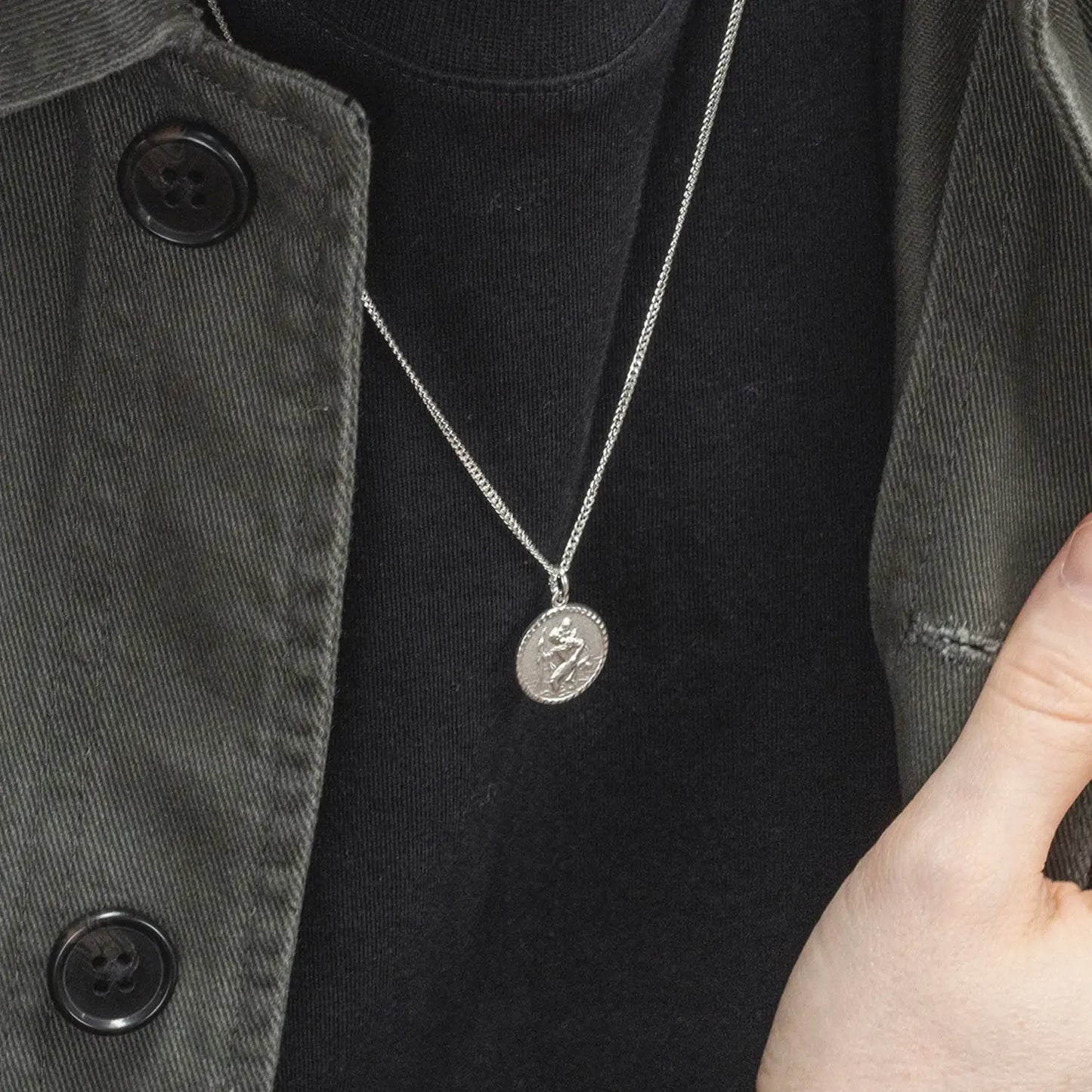 Silver st Christopher necklace with a pendant worn by a man against a black t-shirt