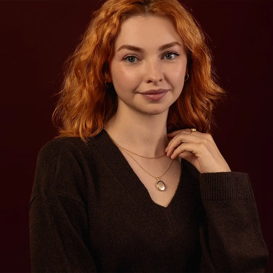 Model wearing a solid 9ct gold oval locket necklace with layered gold chains