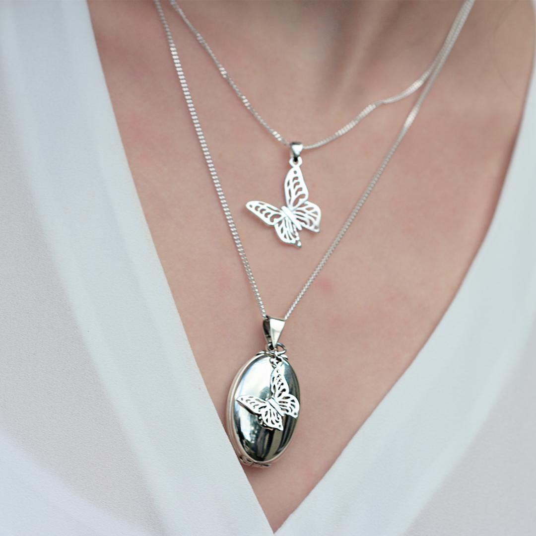 model wearing silver oval shaped locket with butterfly charm