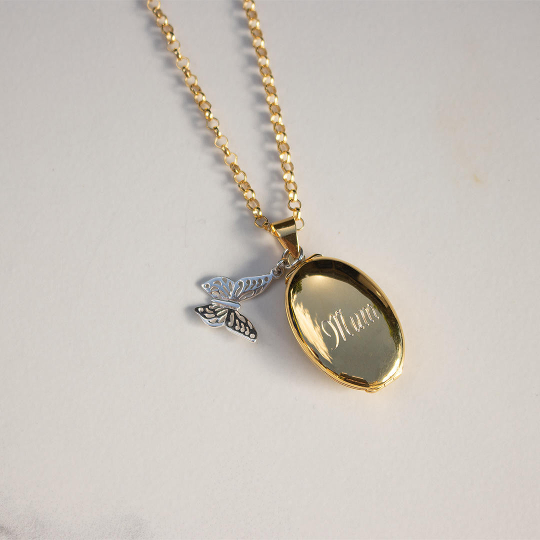 oval locket with butterfly charm on a gold belcher chain 