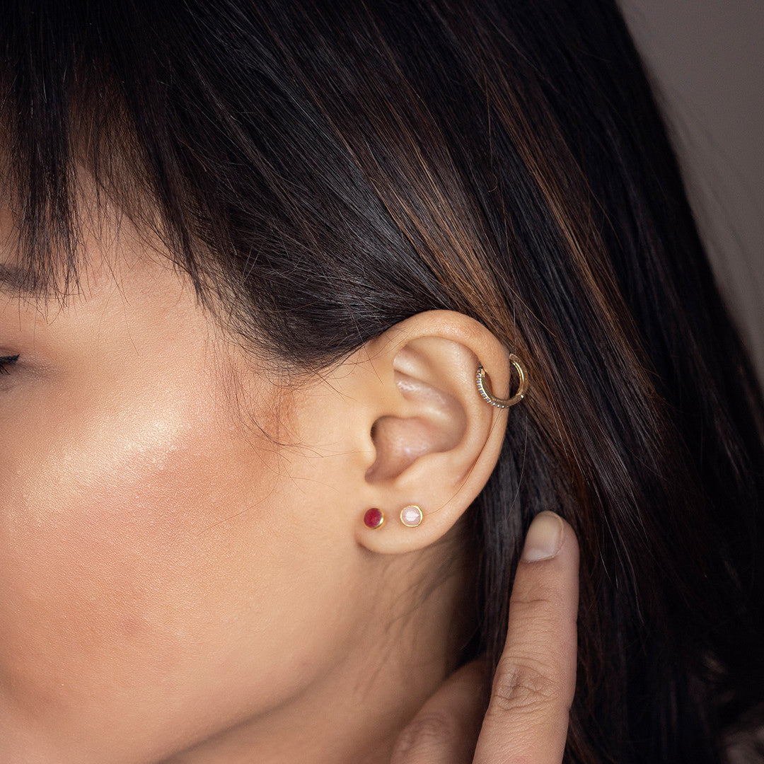Model wearing garnet mini stud earrings in gold