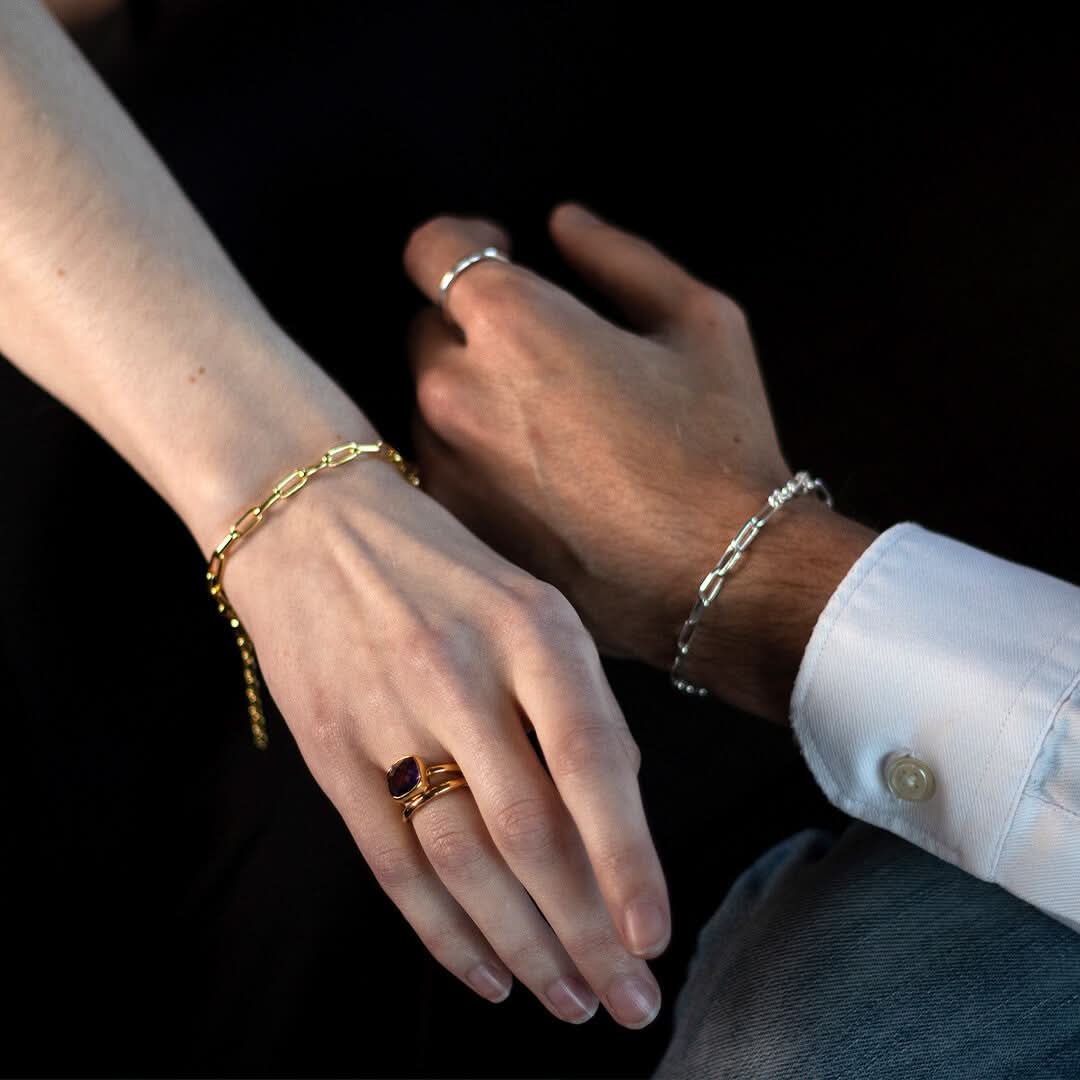 close up of man and women wearing paperclip chain bracelets in gold and silver