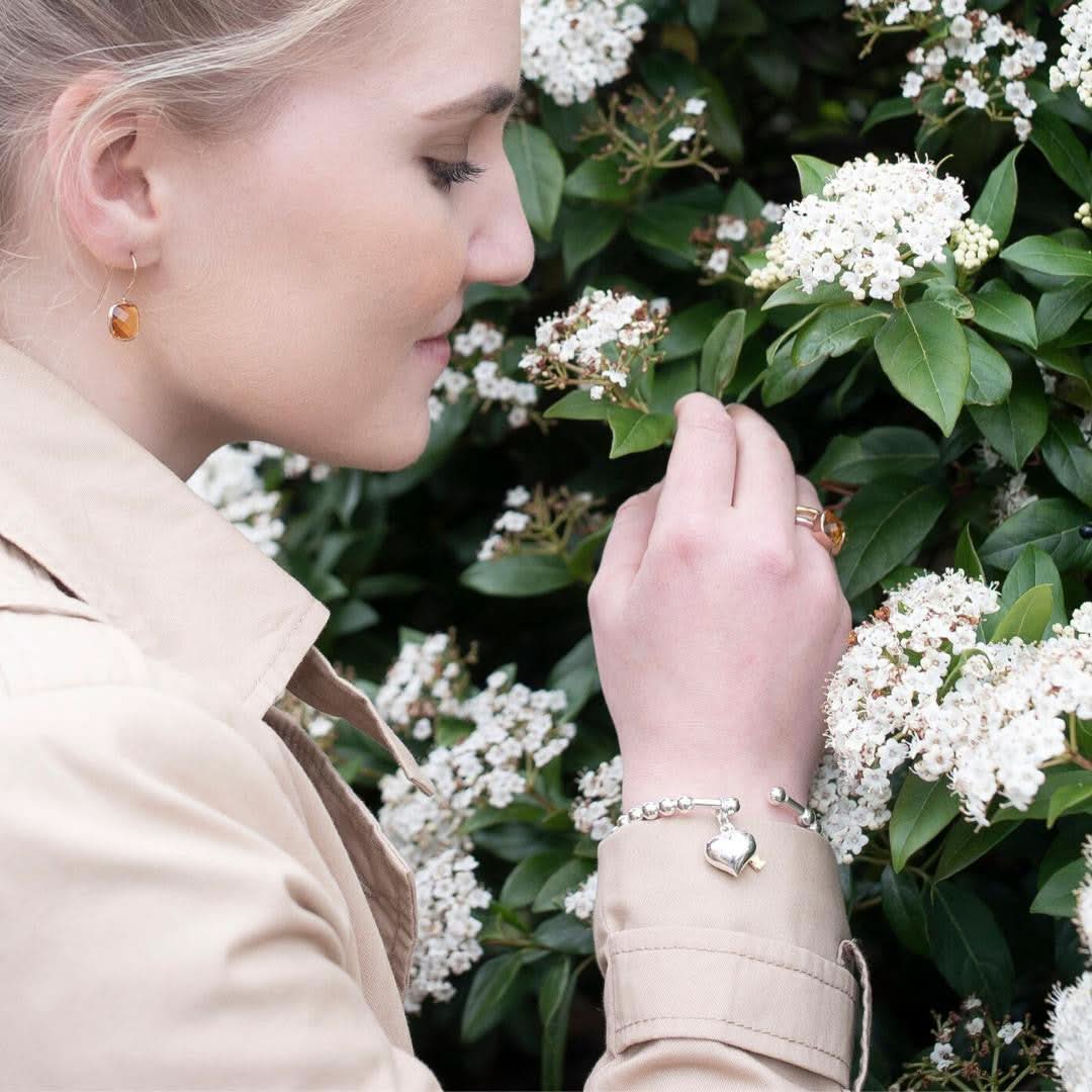 model wearing citrine earrings in gold holding flower