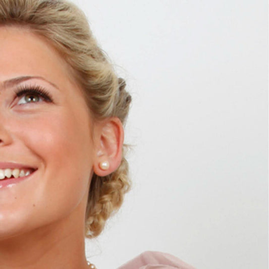 close up of model wearing classic pearl earrings in champagne