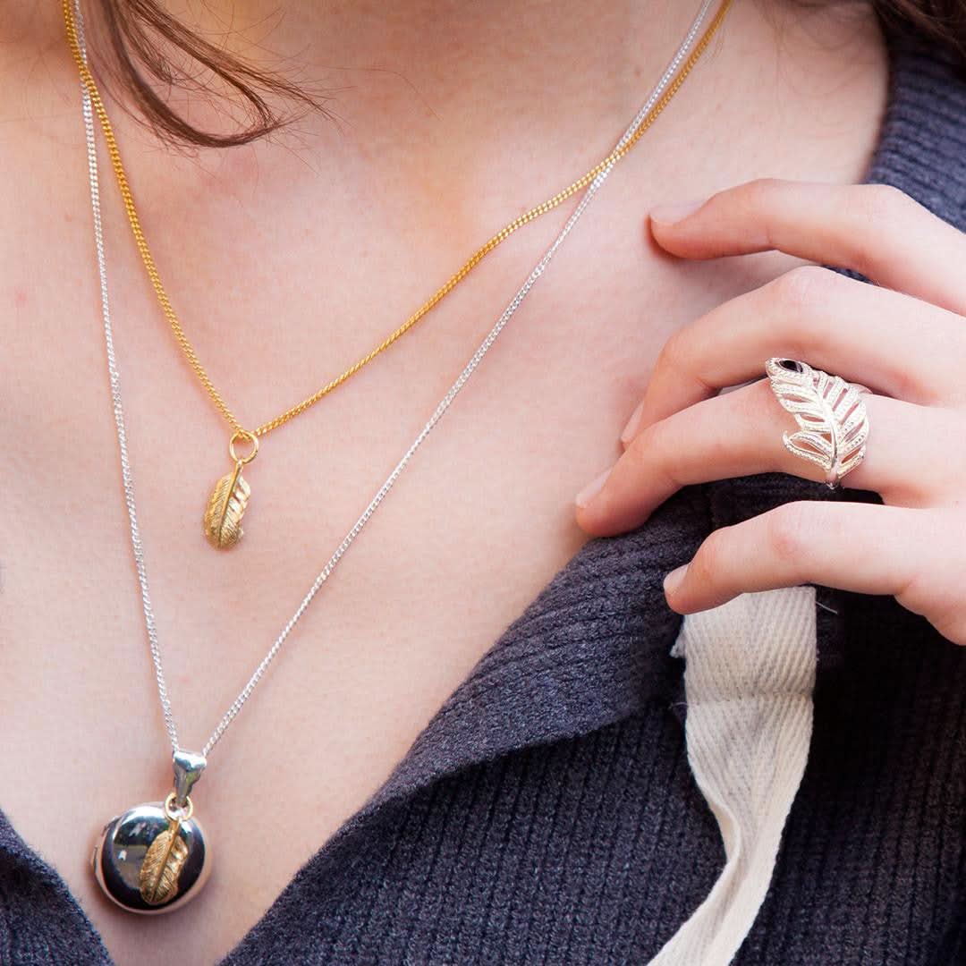 model wearing two pieces of jewellery with gold feather charms attached