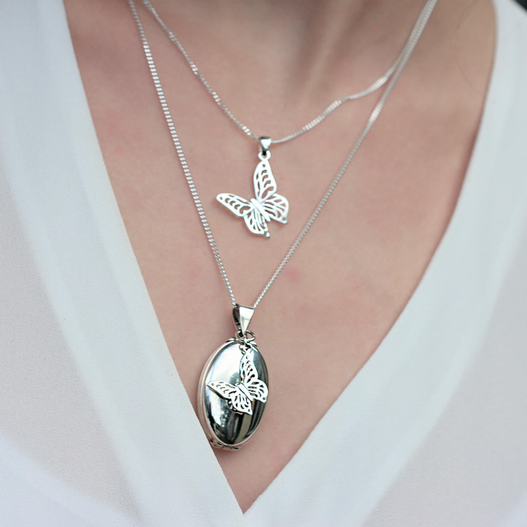 Model wearing white gold oval shaped locket with butterfly charm
