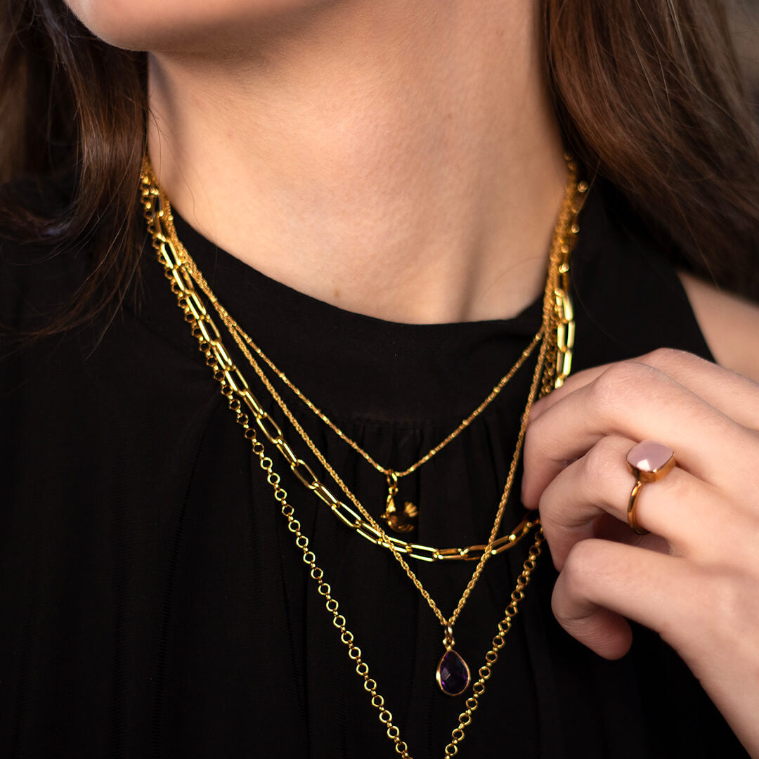model wearing paperclip chain necklace in gold along with other gold jewellery