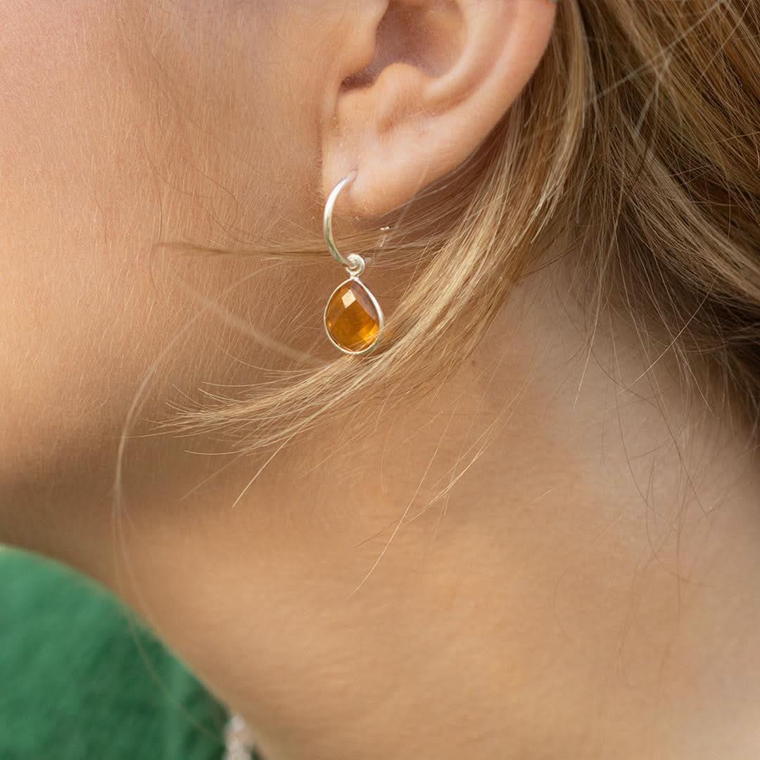 close up of model wearing citrine drop hoop earrings in silver