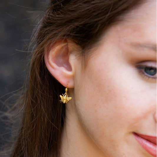 close up of model wearing gold bee earrings