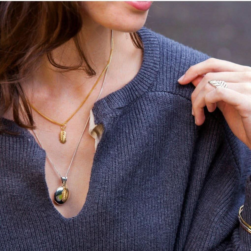 model wearing feather locket in silver with gold feather charm