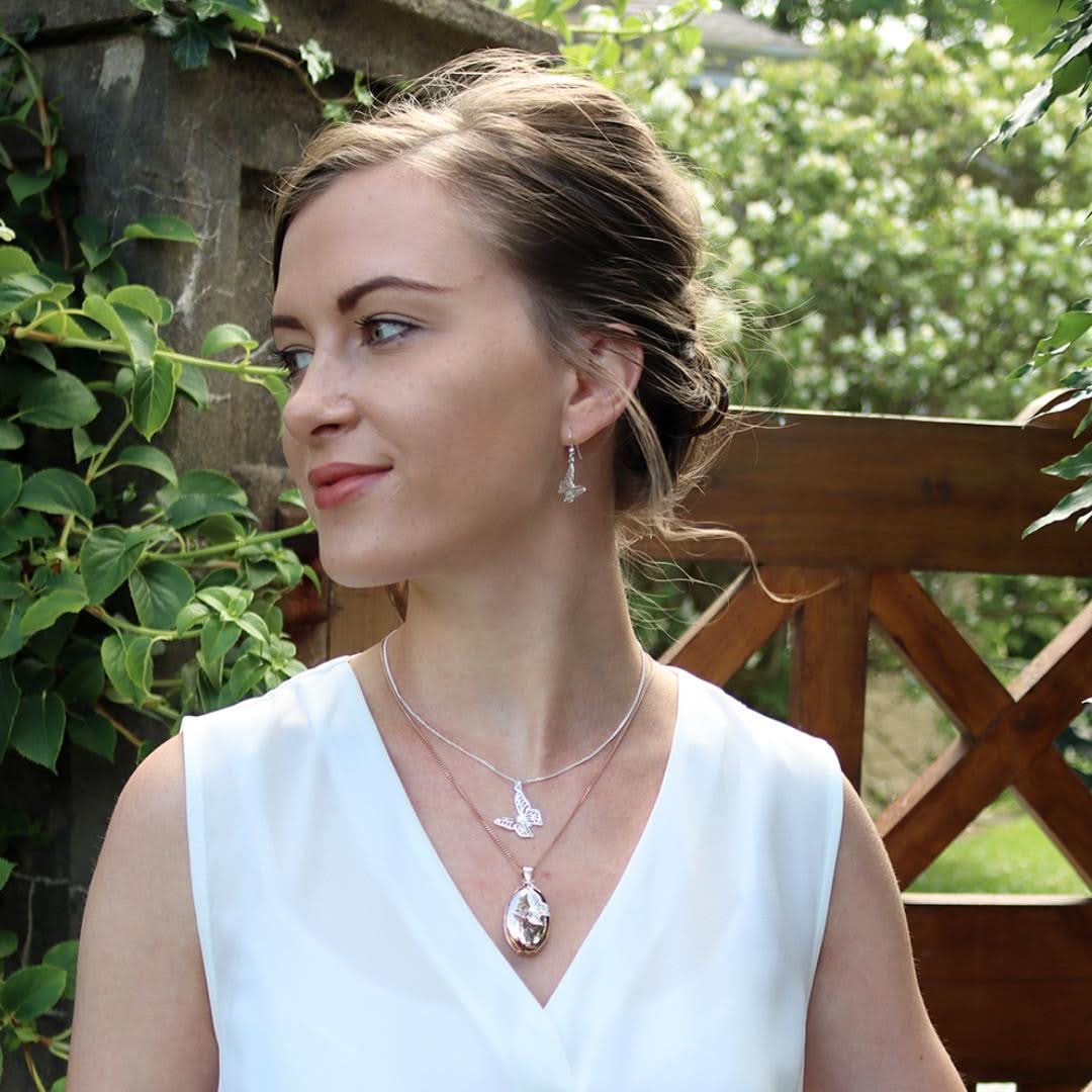 model in white top wearing white gold oval shaped locket with butterfly charm