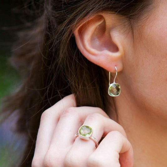 close up of model wearing green amethyst cocktail ring and earrings