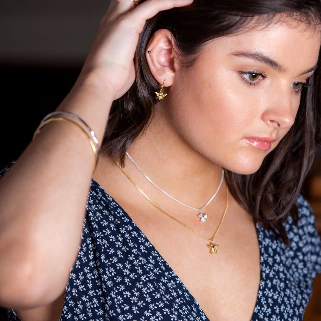 model wearing two bee pendants