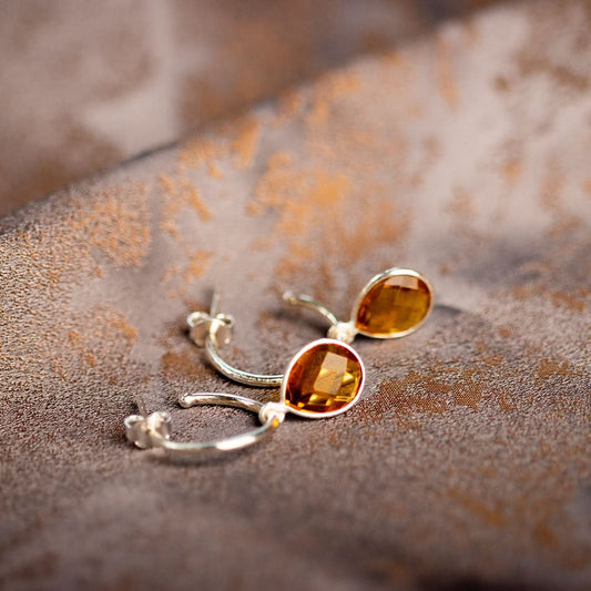 citrine drop hoop earrings in silver on a piece of fabric