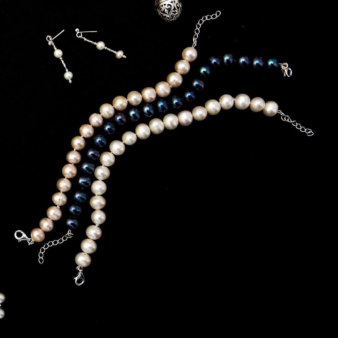 classic pearl bracelets in different colours on a black background