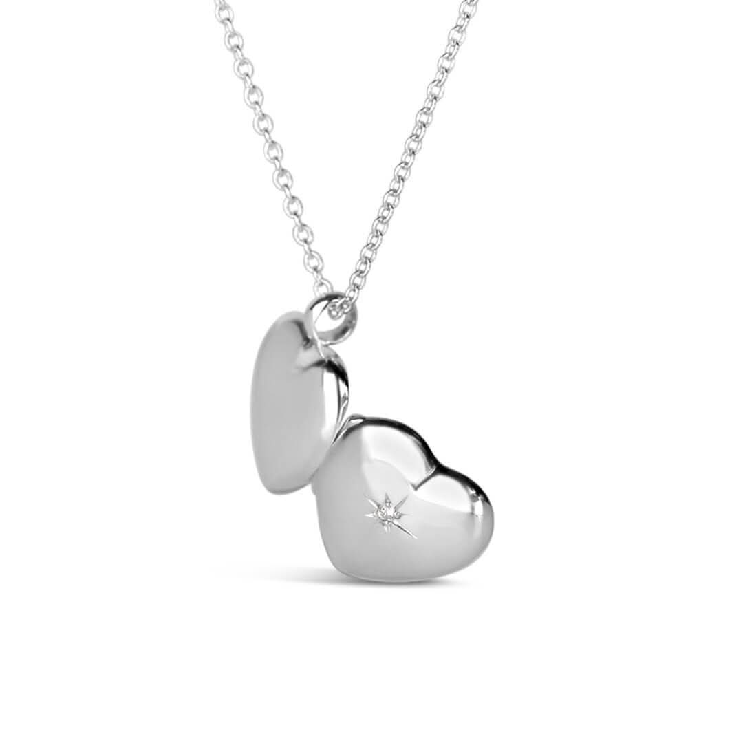 partially opened view of a heart shaped locket in silver to show back and front of locket including diamond decoration on the front