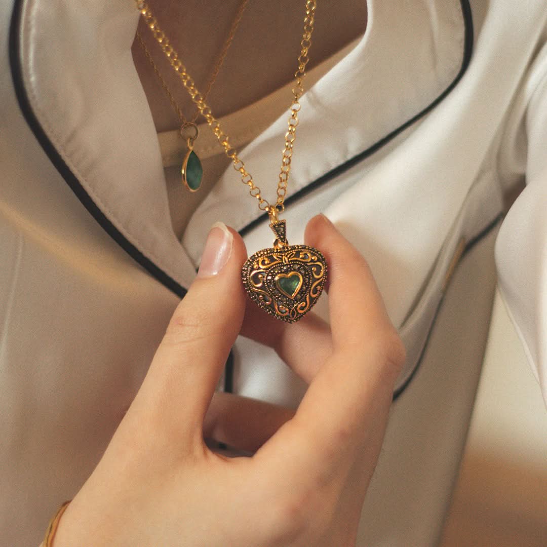 women modelling emerald vintage heart locket in gold with chain