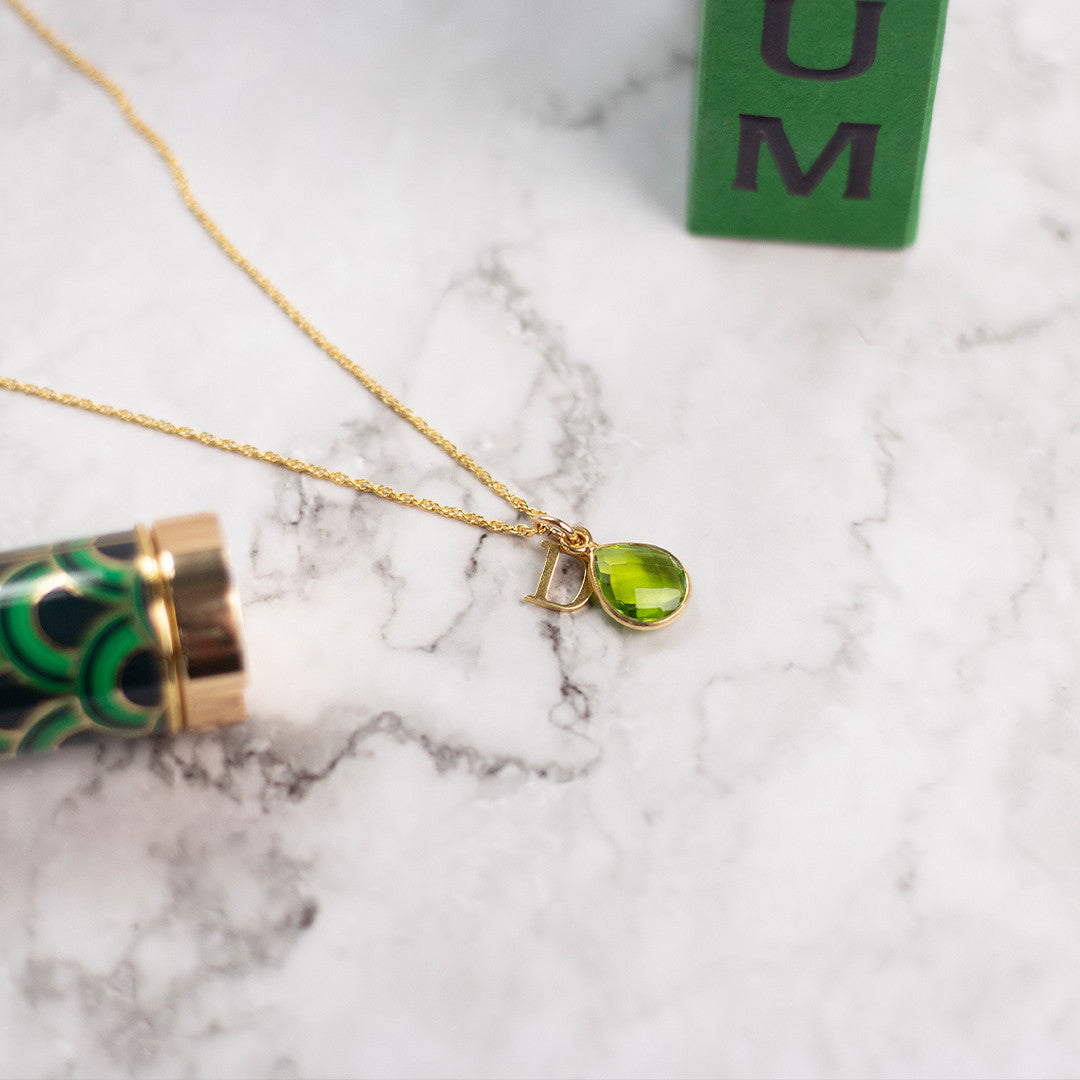 flat lay image of  green peridot gold pendant necklace