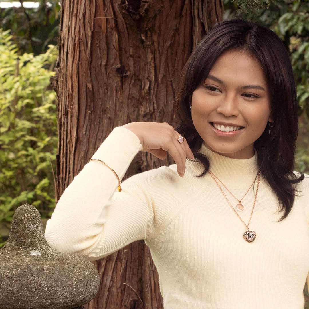 model in cream top wearing rose gold vintage heart locket with gemstone