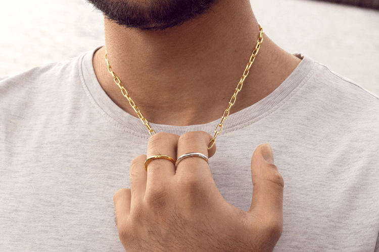 male model wearing gold link necklace and gold and silver rings