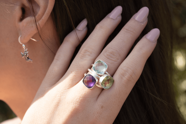 model wearing blue topaz, purple amethyst and green amethyst rings