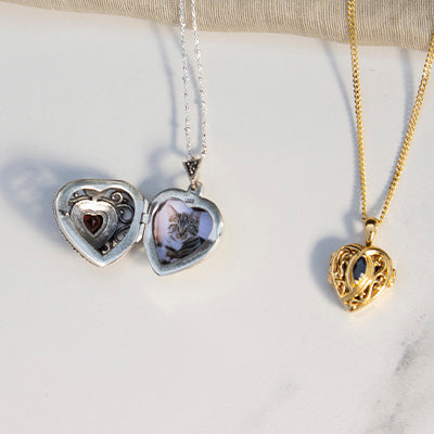 Photograph showing a silver heart locket and a small gold heart locket on a white dish