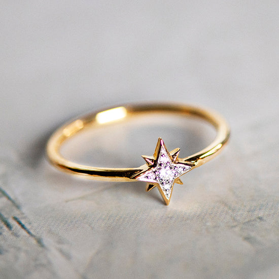 gold ring with a star shaped diamond lying on flat surface